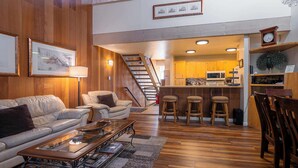 A spacious living area with a leather sofa, a coffee table, and a kitchen in the background. - Creekside Chalet, Stay for 6 (Kings Beach)