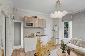 A compact living space with a kitchenette, a sofa, and a dining table. - Charming Modern One-Bed in Vibrant West London (London)