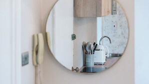 Uno specchio rotondo riflette un angolo cottura con una macchina da caffè, utensili e un telefono.