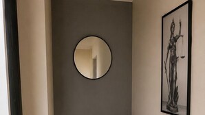Un dormitorio con una cama, un espejo redondo y una obra de arte enmarcada en la pared.
