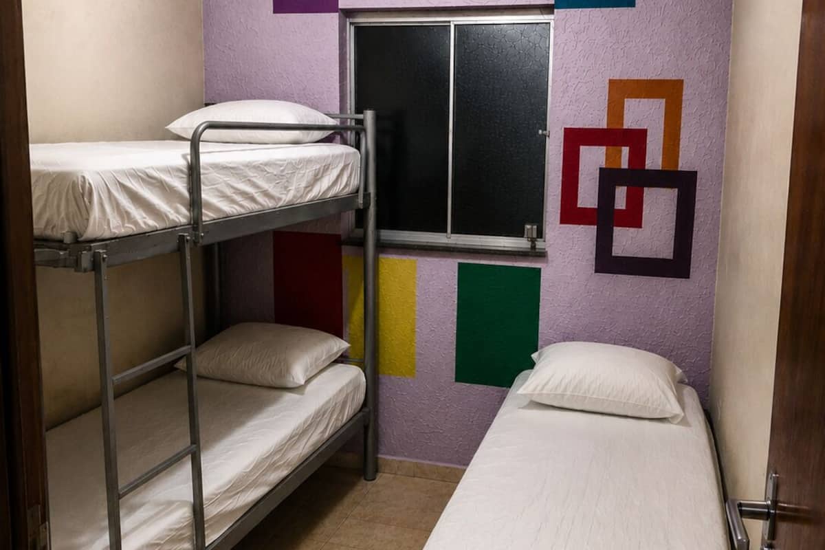 A dormitory room with bunk beds and a window.