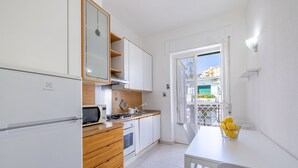 A modern kitchen with white cabinets, a wooden countertop, and a dining area with a table and chairs. - Sea View Central Apartment by Wonderful Italy (Sanremo)