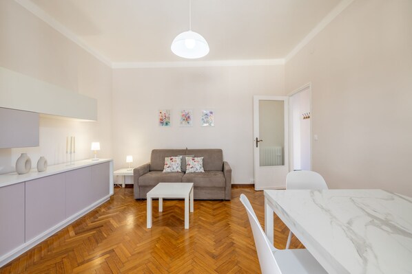A modern living room with a sofa, a coffee table, and a dining table. - Sea View Central Apartment by Wonderful Italy (Sanremo)