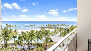 A balcony with a view of a beach, palm trees, and a pool area. - 7th Fl Ilikai | AC | Pool (Honolulu)