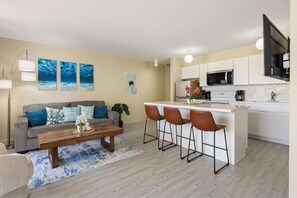 A modern living room with a grey sofa, a wooden coffee table, and a blue patterned rug. - 20th Fl Waikiki Banyan | King | AC | Parking (Honolulu)