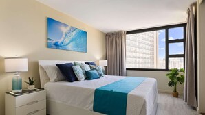 Una camera d'hotel moderna con un letto grande, un comodino con una lampada, una pianta in vaso e vista sulla città dalla finestra.