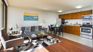A modern living room with a sofa, coffee table, and a painting on the wall. - 29th Fl Waikiki Banyan | Diamond Head Views | Parking | AC (Honolulu)