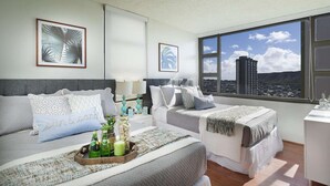 A modern hotel room with two beds, a large window with a city view, and artwork on the walls. - 29th Fl Waikiki Banyan | Diamond Head Views | Parking | AC (Honolulu)