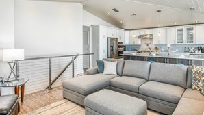 A modern living room with a sectional sofa, a glass coffee table, and a staircase leading to another level. - Nstar By The Sea (St. Augustine)