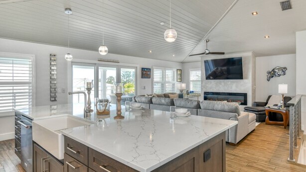 A spacious kitchen with a large island, modern appliances, and a dining area with a gray sofa. - Nstar By The Sea (St. Augustine)