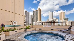 Une piscine sur le toit, agrémentée d’un panneau d’avertissement, de chaises longues et offrant une vue sur les gratte-ciel.