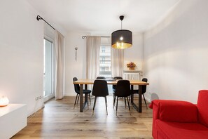 Un espace repas comprenant une table en bois, des chaises noires et un canapé rouge.
