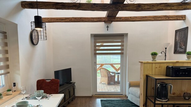 A compact living space with a dining area, kitchen, and a view to an outdoor deck. - The Hungarian Valley (Szellő)