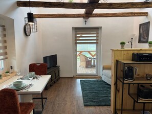 A compact living space with a dining area, kitchen, and a view to an outdoor deck. - The Hungarian Valley (Szellő)