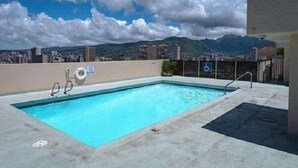 Une piscine sur le toit offrant une vue dégagée sur la ville et les montagnes en arrière-plan.