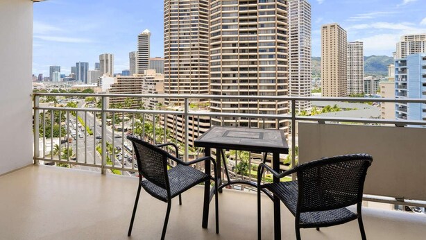 Ein Balkon mit Tisch und Stühlen mit Blick auf eine Stadtlandschaft mit Hochhäusern.