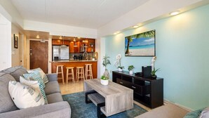 Ein modernes Wohnzimmer mit einem grauen Sofa, einem Holztisch und einer Küche im Hintergrund.