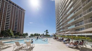 A rooftop pool area with lounge chairs and a swimming pool surrounded by tall buildings. - Ilikai 14th Fl Studio | City View | AC | Pool (Honolulu)