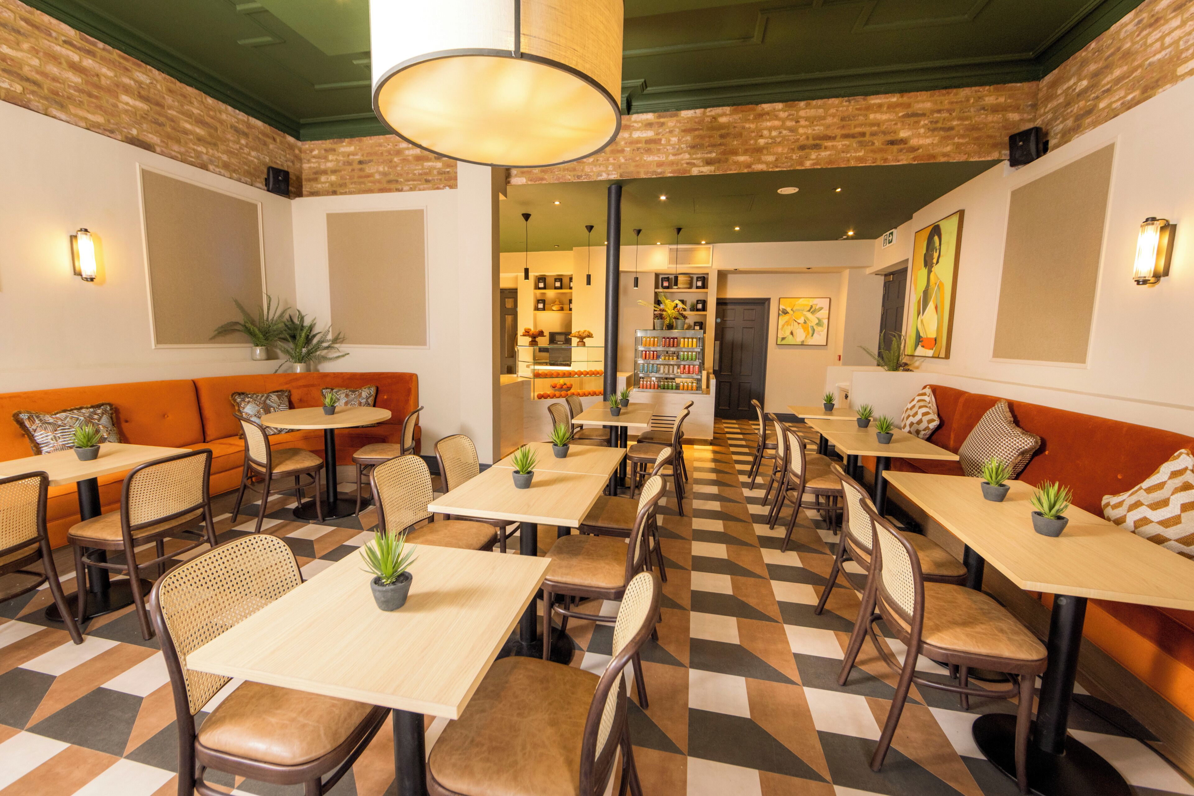 A restaurant with checkered flooring, wooden tables and chairs, and potted plants.