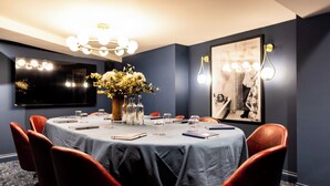 A conference room with a round table, red chairs, a floral centerpiece, and a framed photograph on the wall. - The Royal Bell (Bromley)
