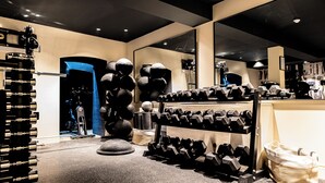 A gym with exercise equipment, including dumbbells and a rowing machine. - The Royal Bell (Bromley)