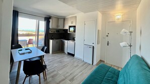 A compact kitchenette with a microwave, a small fridge, and a dining area with a table and chairs. - Sea view, calm and comfort in the village (Hyères)