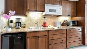 Una cocina con armarios de madera, microondas, cafetera, tostadora y lavavajillas.