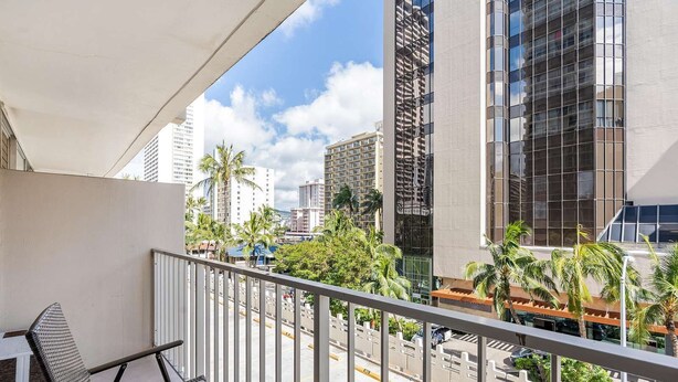 Uma varanda com vista para edifícios altos e palmeiras.