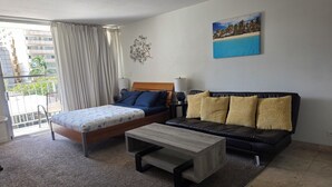 Une chambre à coucher avec un lit, un canapé, une table basse et un tableau représentant une plage.