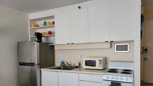 Une cuisine compacte équipée d’un réfrigérateur en acier inoxydable, d’un four à micro-ondes et d’une cuisinière.