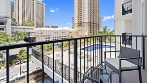 A balcony with a pool, overlooking a cityscape with tall buildings and palm trees. - 3rd Fl Palms Waikiki Studio Overlooking the Pool | Parking (Honolulu)