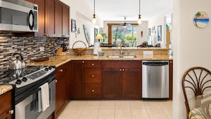Una cocina moderna con armarios de madera, un microondas de acero inoxidable, un hervidor, un lavavajillas y una isla grande con fregadero.