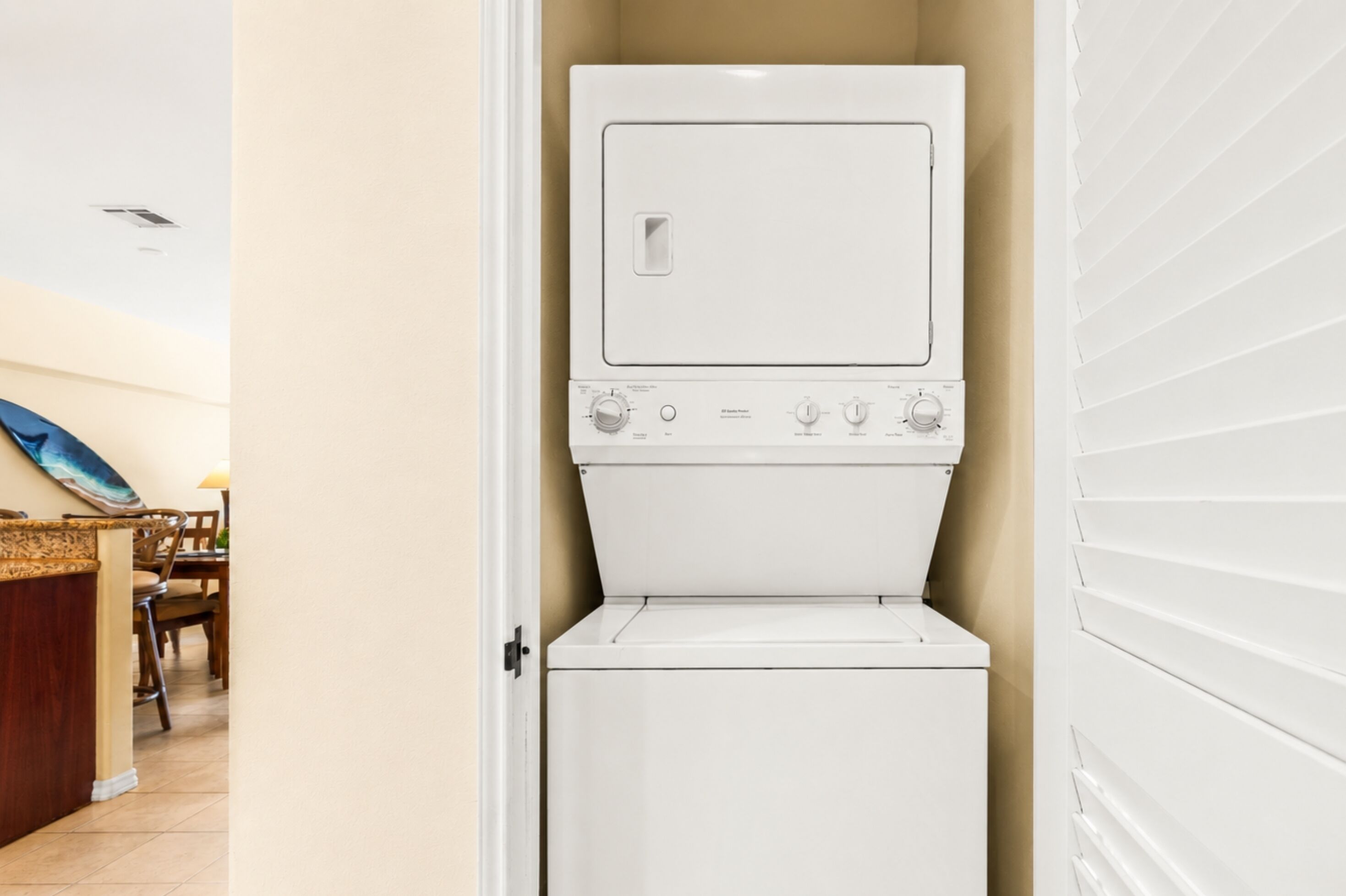 A laundry room with a washer and dryer, a wooden chair, and a tiled floor.