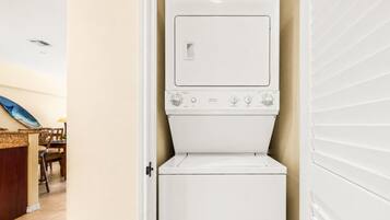 A laundry room with a washer and dryer, a wooden chair, and a tiled floor.
