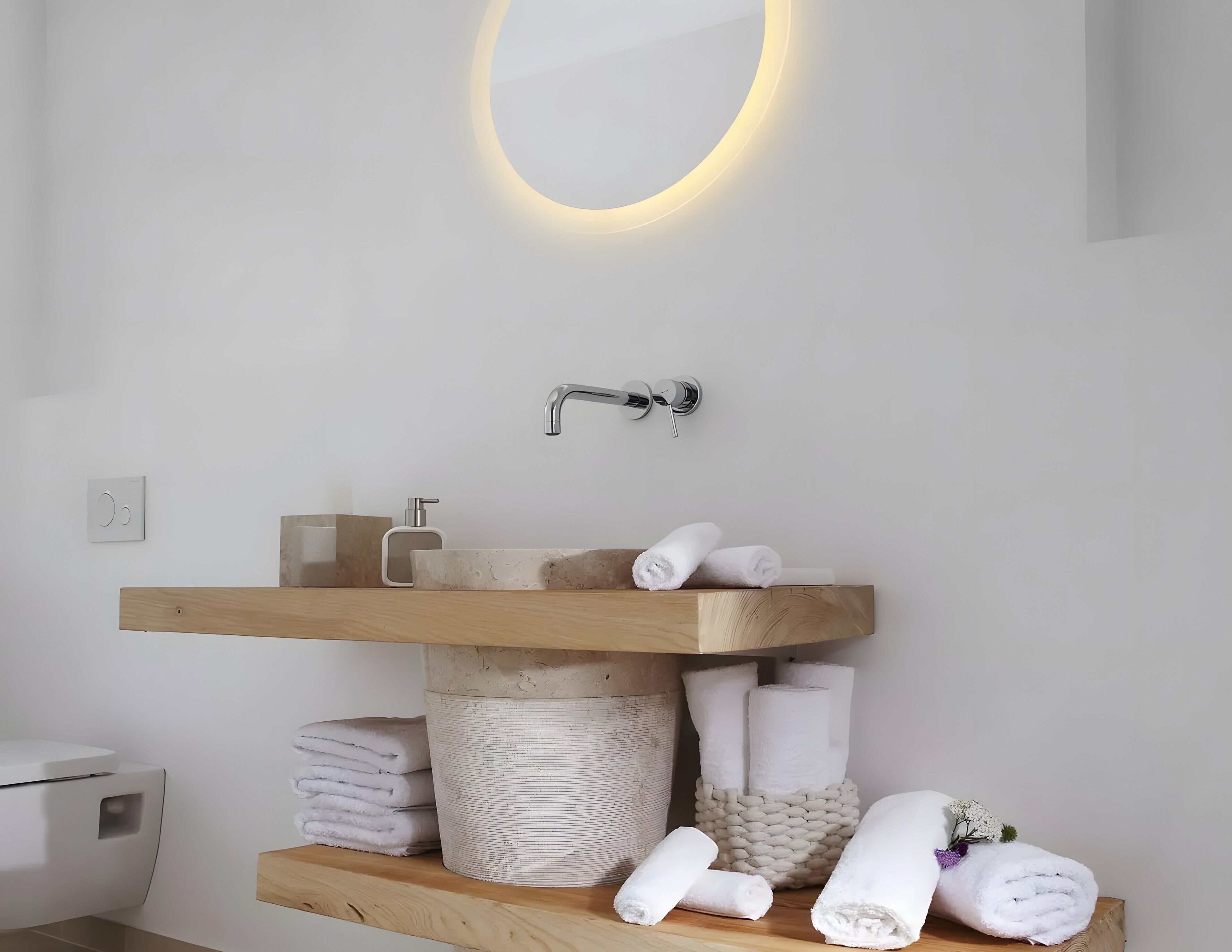 A modern bathroom with a wooden vanity, a round mirror, and a built-in sink.