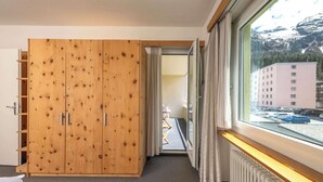 A hotel room with a wooden wardrobe, a bed, a radiator, and a window with a view of a building and parked cars. - Lake-Side Stay, Newly Renovated,  Free Parking (San Maurizio)