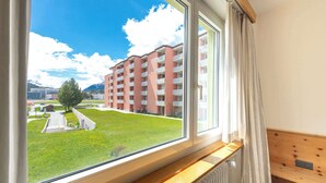 A hotel room with a large window offering a view of a building complex and a grassy area. - Lake-Side Stay, Newly Renovated,  Free Parking (San Maurizio)