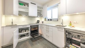 A modern kitchen with white cabinets, a built-in oven, a dishwasher, and a window providing natural light. - Lake-Side Stay, Newly Renovated,  Free Parking (San Maurizio)