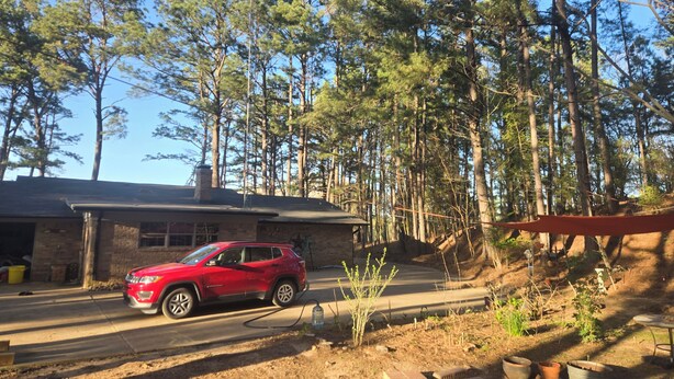 Een rode SUV geparkeerd voor een rustieke houten chalet met een stenen gevel, omringd door hoge dennenbomen.
