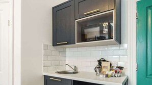 Une cuisine de taille réduite, dotée de meubles de rangement sombres, d’un four à micro-ondes encastré et d’un lave-vaisselle.