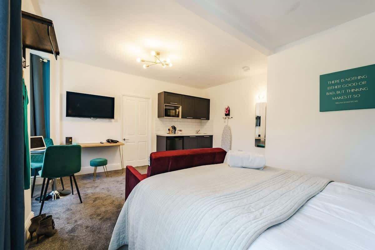 Ett hotellrum med en säng, ett skrivbord, en tv, en mikrovågsugn och en spegel som är monterad på väggen.