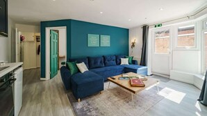 Un saló modern amb una paret d'accent color turquesa, un sofà seccional blau i una taula de centre de fusta amb llibres.