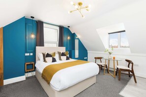 Un dormitorio moderno con una cama grande, una mesita, dos sillas y un tragaluz.