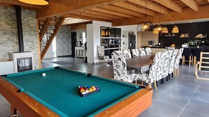 Een pooltafel met ballen, een eethoek met gestreepte stoelen en een keuken met moderne apparatuur.