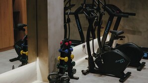 A gym with exercise equipment including a treadmill, elliptical, and kettlebells. - Lithos villa by Elements villas (Kokkino Chorio)