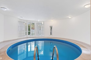 An indoor swimming pool with clear glass walls, a tiled floor, and a ceiling with recessed lighting. - Black Dragon Castle (Prague 20)