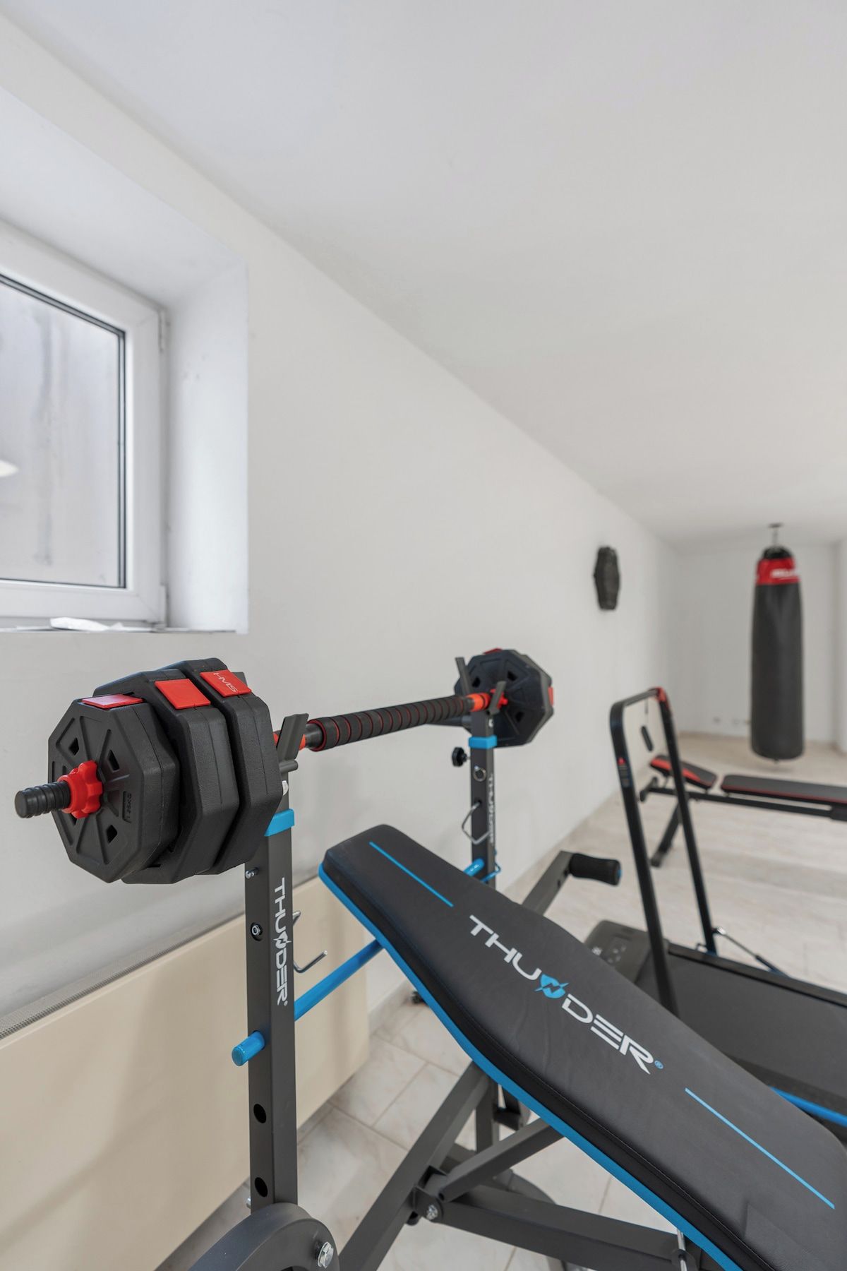 Ein Fitnessraum mit einer Bank, einer Hantelbank und einem Sandsack.