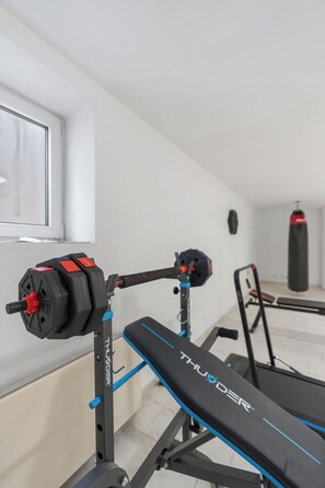 A gym with a bench, weight bench, and a punching bag. - Black Dragon Castle (Prague 20)