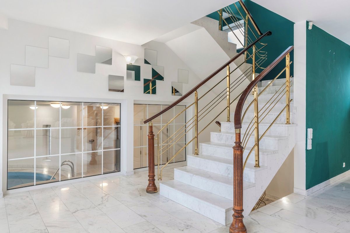 A spacious interior with a marble staircase, a glass-enclosed area, and a teal accent wall.