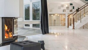 Ein modernes Wohnzimmer mit Kamin, Treppe und großem Fenster.